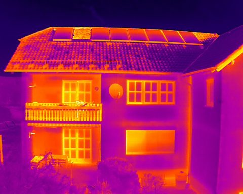 Wärmebild eines Hauses mit Balkon und Solarpanelen auf dem Dach.